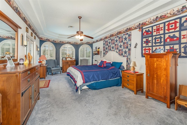 bedroom featuring ceiling fan, visible vents, a raised ceiling, and carpet flooring