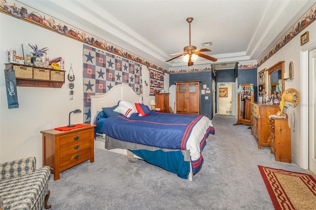 bedroom featuring a raised ceiling, visible vents, a ceiling fan, light carpet, and a textured ceiling