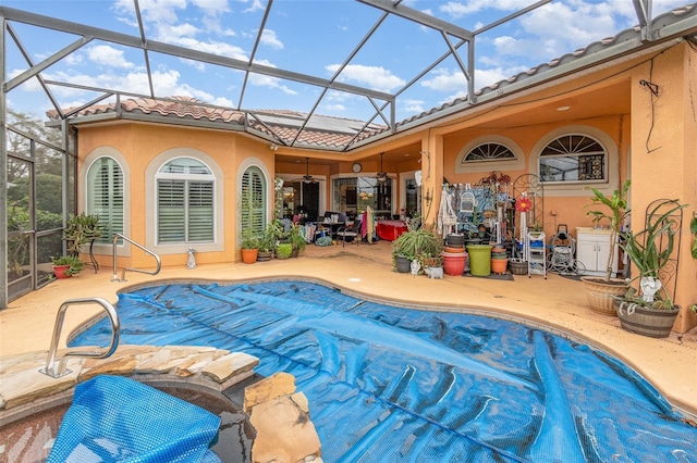 view of pool featuring glass enclosure, a covered pool, and a patio