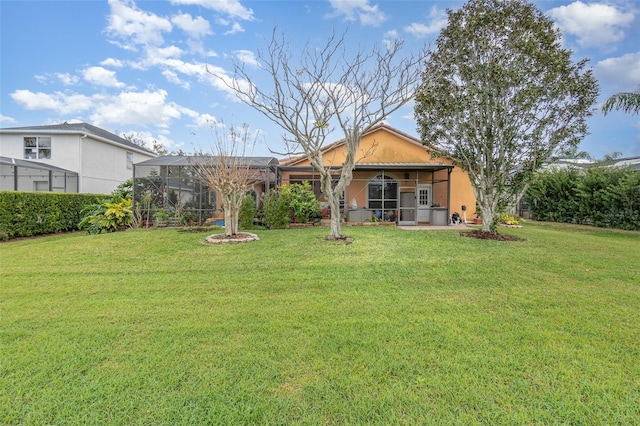 rear view of house featuring a yard, glass enclosure, and stucco siding