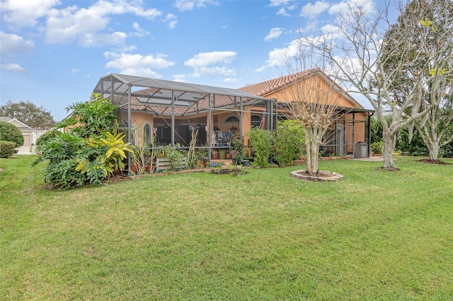 back of house with a yard, a lanai, a tiled roof, and stucco siding