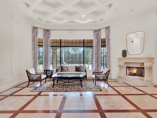 living area with baseboards, coffered ceiling, a premium fireplace, a high ceiling, and a decorative wall