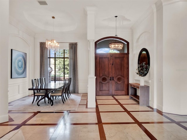 foyer featuring a chandelier, ornamental molding, a decorative wall, and baseboards