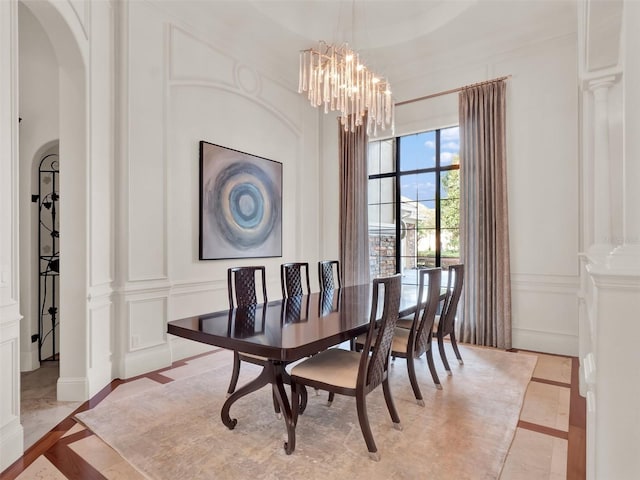 dining area with a chandelier, arched walkways, and a decorative wall