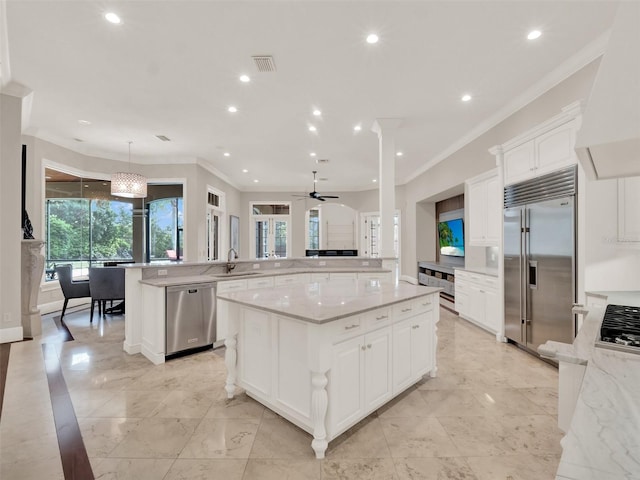 kitchen featuring stainless steel appliances, a spacious island, a sink, white cabinets, and wall chimney exhaust hood