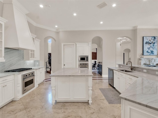 kitchen with visible vents, appliances with stainless steel finishes, a center island, custom exhaust hood, and a sink