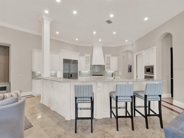 kitchen featuring premium range hood, baseboards, tasteful backsplash, and built in appliances