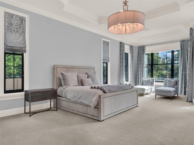 carpeted bedroom featuring ornamental molding, a raised ceiling, and baseboards