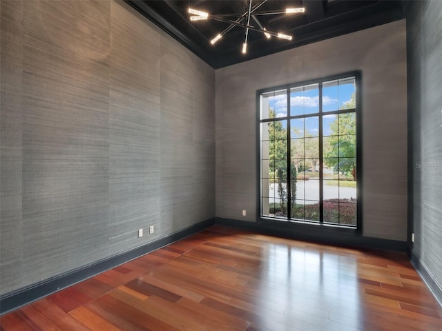 spare room featuring a notable chandelier, baseboards, and wood finished floors