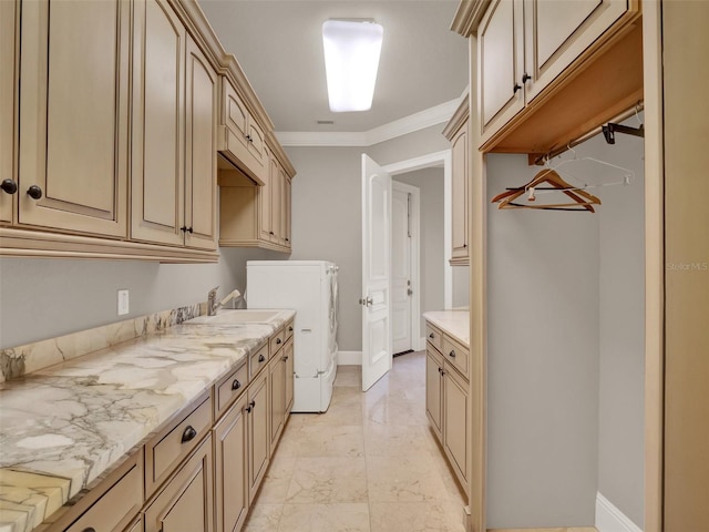 laundry area featuring marble finish floor, crown molding, washer and clothes dryer, cabinet space, and a sink