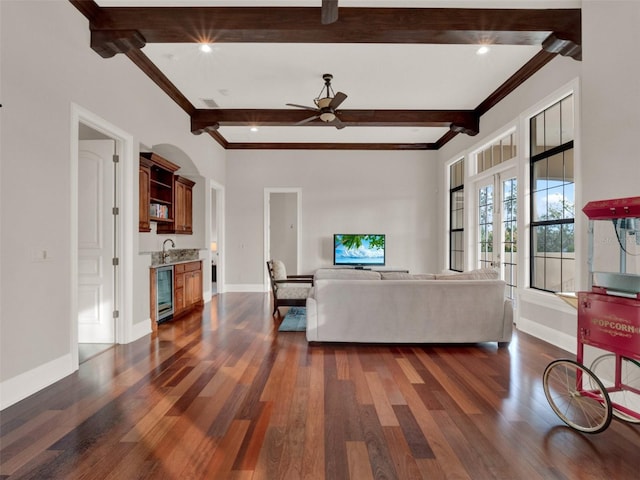 living room featuring dark wood-style flooring, wine cooler, beamed ceiling, and baseboards