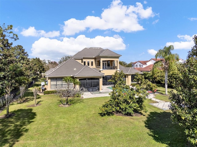 back of property with a lawn, a balcony, a sunroom, a tile roof, and stucco siding