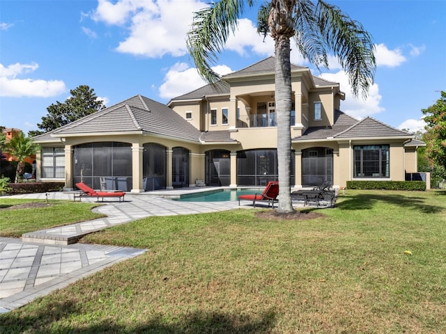 rear view of house featuring stucco siding, a lawn, a sunroom, a balcony, and an outdoor pool