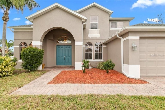 view of exterior entry featuring an attached garage and stucco siding