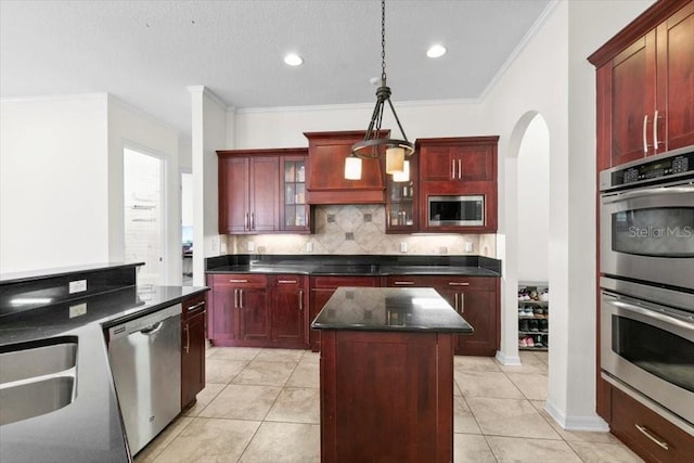 kitchen with dark countertops, a kitchen island, appliances with stainless steel finishes, and dark brown cabinets