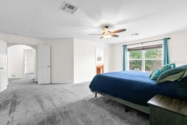 carpeted bedroom with ceiling fan, visible vents, arched walkways, and baseboards