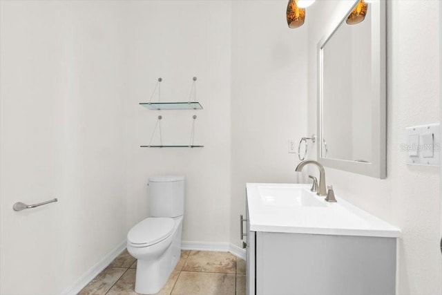 bathroom with toilet, baseboards, vanity, and tile patterned floors