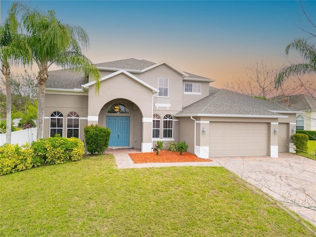 traditional-style house with a front lawn, an attached garage, and stucco siding