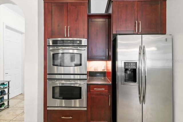 kitchen with reddish brown cabinets, dark countertops, and stainless steel appliances