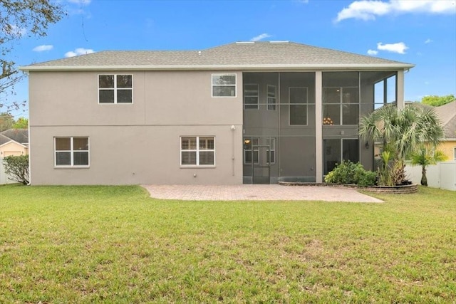 rear view of property featuring a yard, a patio area, a sunroom, and stucco siding