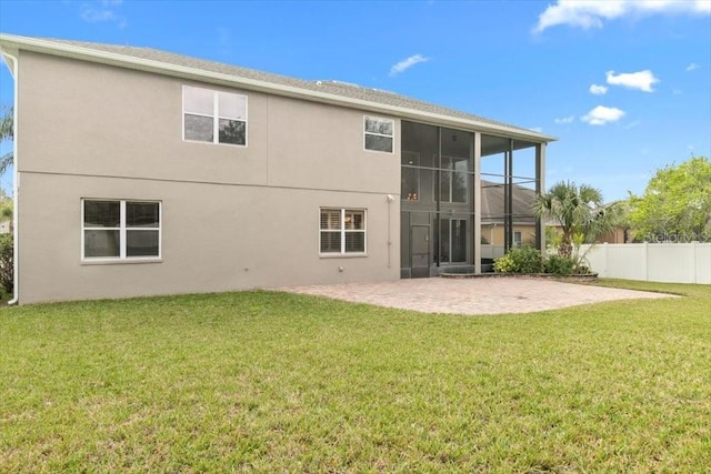 rear view of property featuring fence, a sunroom, a yard, stucco siding, and a patio area