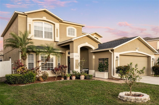 view of front of property featuring fence, a yard, stucco siding, concrete driveway, and a garage