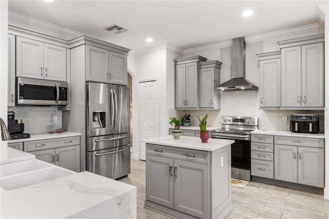 kitchen featuring light wood-type flooring, visible vents, gray cabinets, appliances with stainless steel finishes, and wall chimney range hood