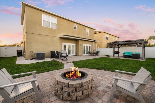 back of house at dusk featuring central AC unit, french doors, a fenced backyard, and a gate