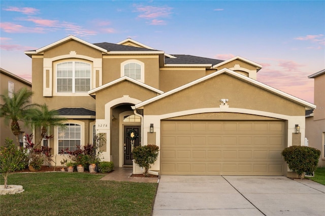 view of front of property featuring stucco siding, concrete driveway, and a yard