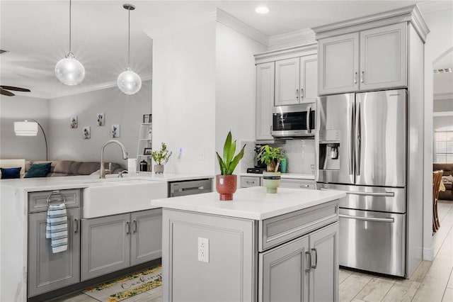 kitchen with crown molding, open floor plan, gray cabinets, stainless steel appliances, and a sink