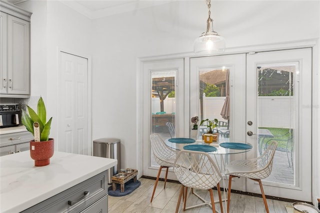 dining room featuring light wood-type flooring, crown molding, and french doors