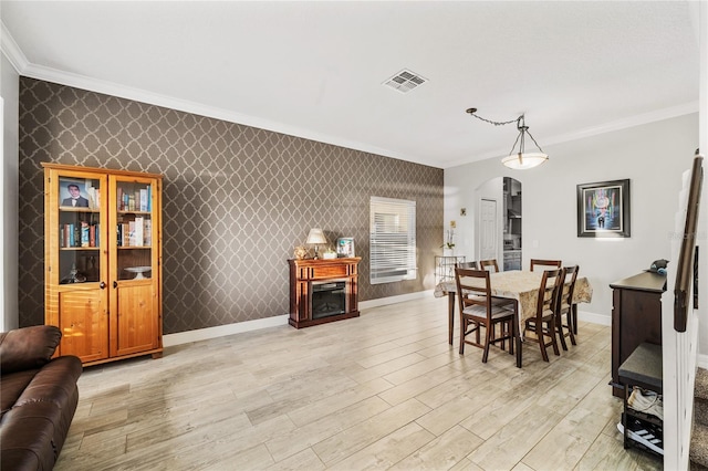 dining space featuring wallpapered walls, arched walkways, visible vents, and baseboards