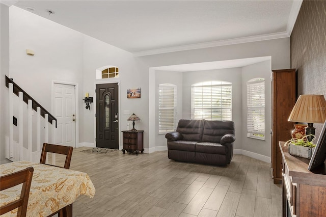 interior space featuring stairway, baseboards, light wood-type flooring, and ornamental molding