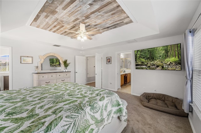 carpeted bedroom with baseboards, ensuite bath, ceiling fan, wood ceiling, and a raised ceiling