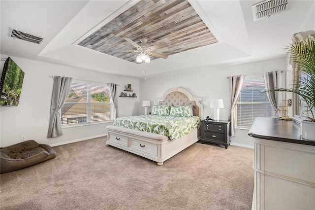 bedroom featuring a raised ceiling, visible vents, and light carpet