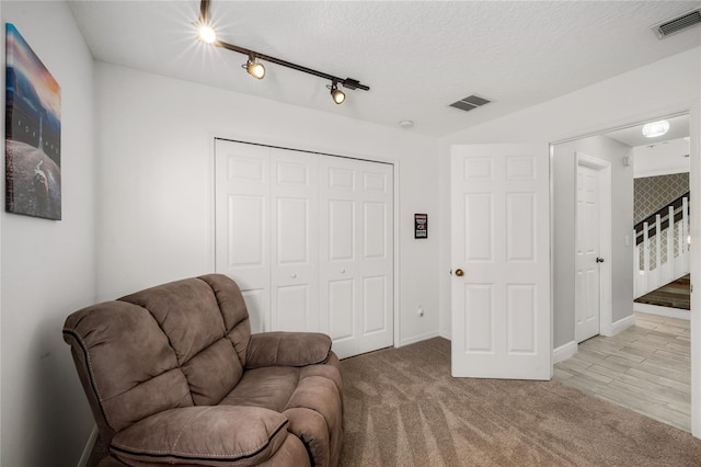 living area with stairs, carpet flooring, visible vents, and a textured ceiling