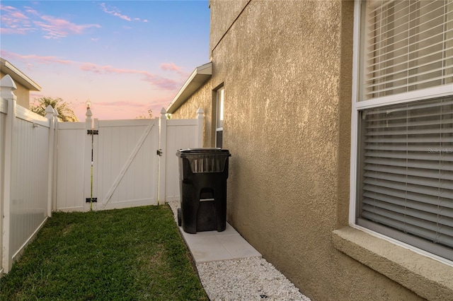 view of property exterior with stucco siding, fence, and a gate