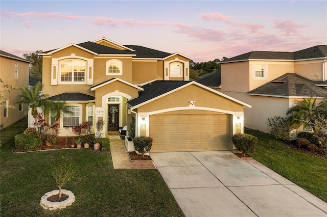 view of front facade with stucco siding, a garage, a yard, and driveway