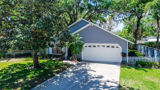 view of front of house with a front yard, concrete driveway, an attached garage, and fence