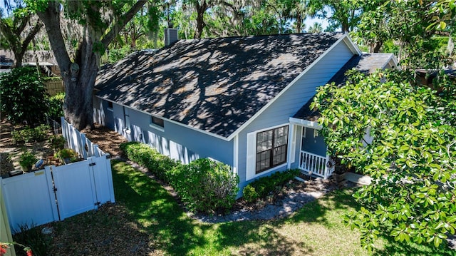exterior space featuring a lawn, roof with shingles, fence private yard, and a gate