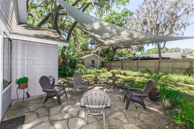 view of patio with an outbuilding and fence