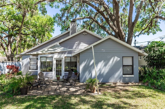 rear view of house featuring a lawn, a chimney, and a patio area