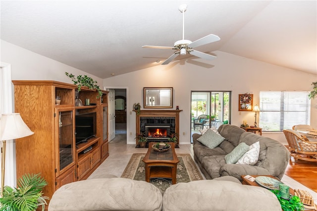 living area featuring ceiling fan, vaulted ceiling, and a tile fireplace