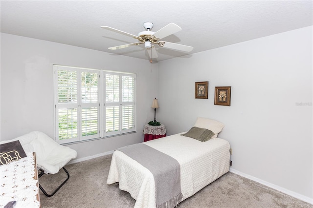 bedroom featuring a textured ceiling, baseboards, carpet floors, and ceiling fan