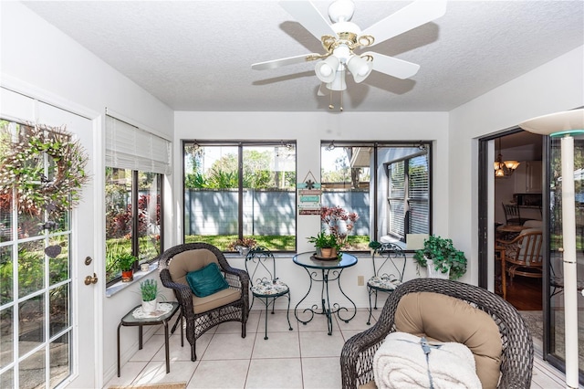sunroom / solarium featuring tile patterned flooring, a ceiling fan, and a textured ceiling