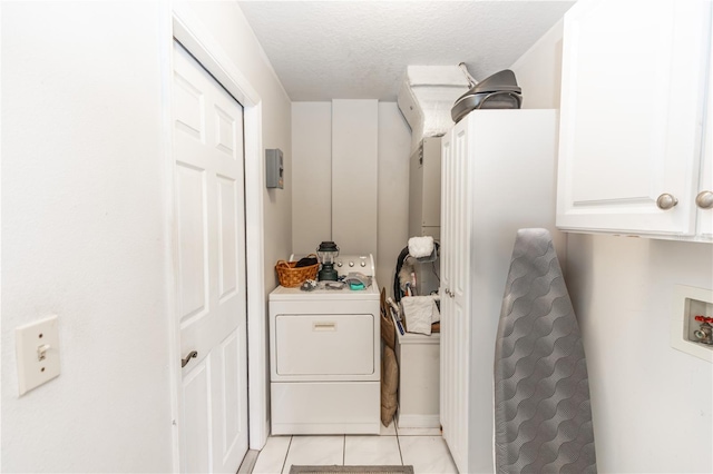 clothes washing area featuring light tile patterned flooring, cabinet space, a textured ceiling, and washer / clothes dryer