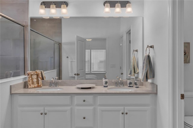 bathroom featuring double vanity, a sink, toilet, and a shower stall