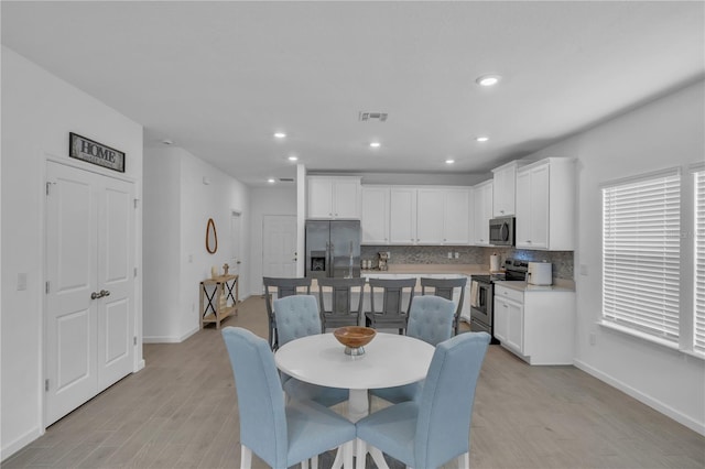 dining area with light wood-style floors, recessed lighting, visible vents, and baseboards