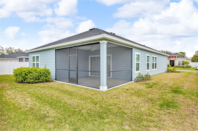 rear view of house with a sunroom, a lawn, and fence