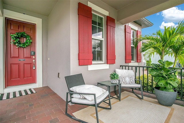 doorway to property with covered porch and stucco siding